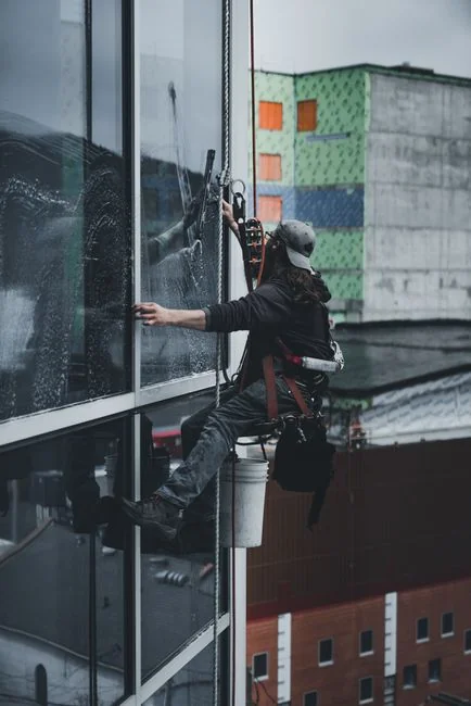 team-02 Un homme méconnaissable portant des gants en latex jaunes nettoie un robinet doré dans la salle de bain, tout en faisant le ménage à la maison avec une éponge orange et du détergent